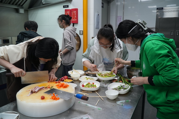 图说:师生在学校食堂后厨烹饪制作