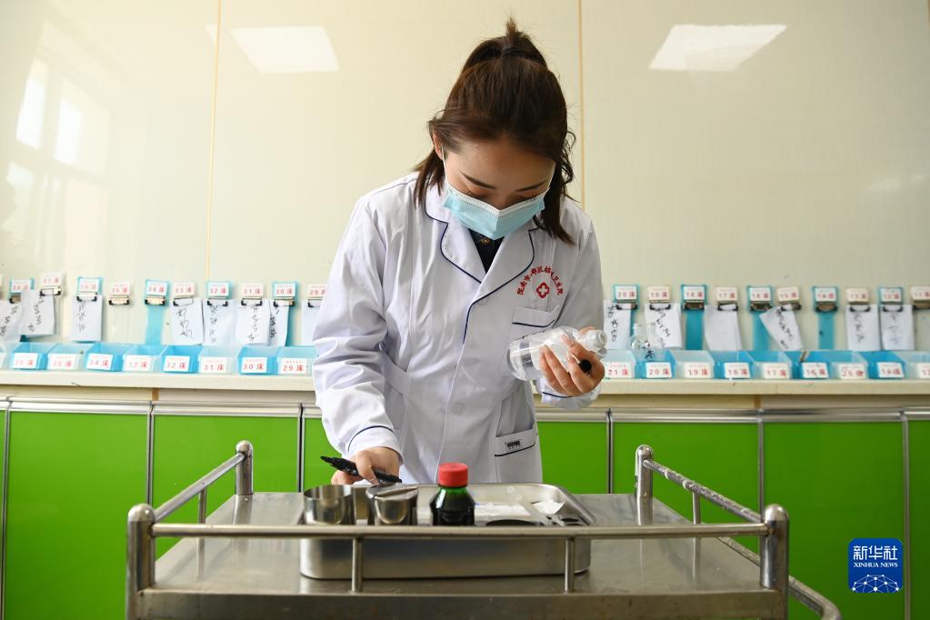 在武都区桔柑镇卫生院住院部护士站,李瑞给患者配药(5月11日摄).