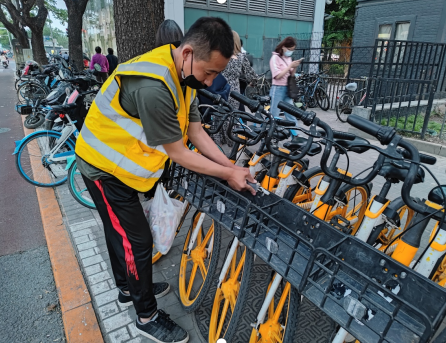 ▲朝阳区亮马桥地铁口共享单车运维员清理小广告 摄影：朱建国