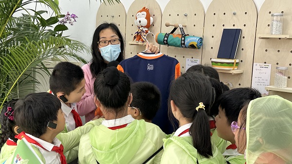 图说:孩子们好奇地观摩塑料瓶回收制成的校服&nbsp;&nbsp;&nbsp; 来源