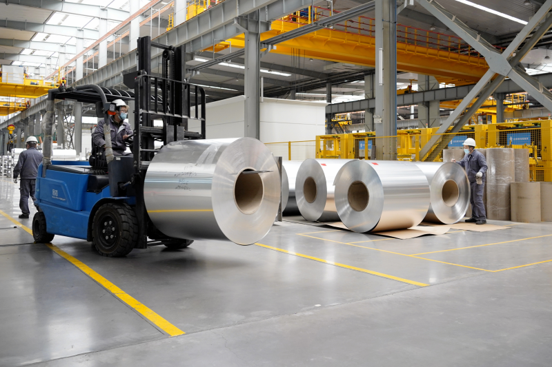 河南郑州一家重点民营企业的工业标准化厂房内,工人正在运输铝箔卷.