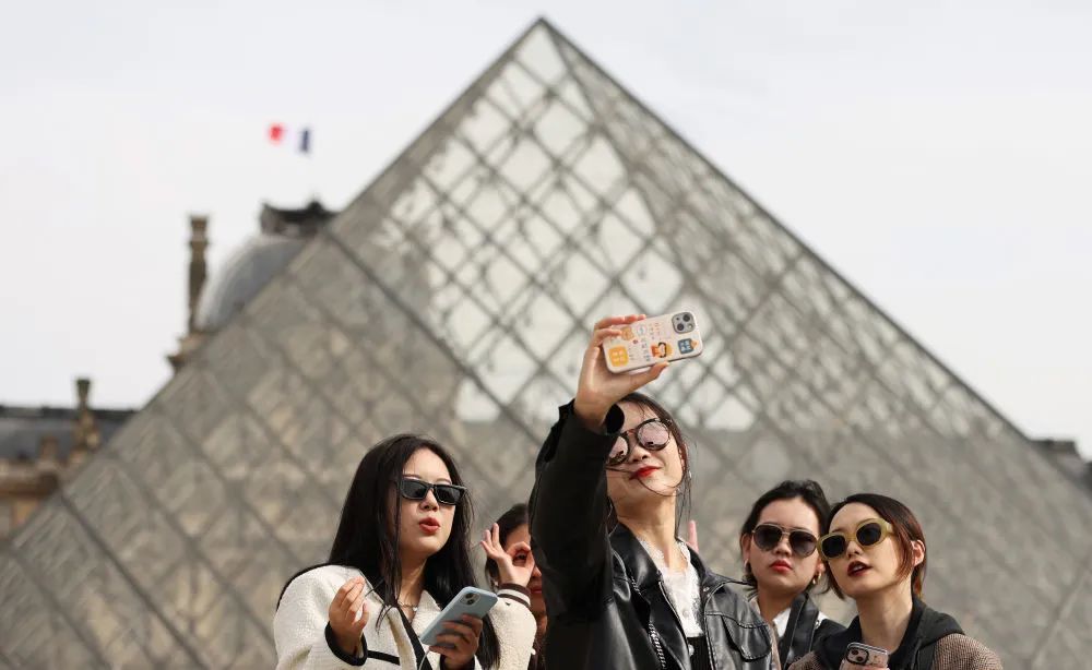 下图:中国游客在法国巴黎卢浮宫的玻璃金字塔前自拍.