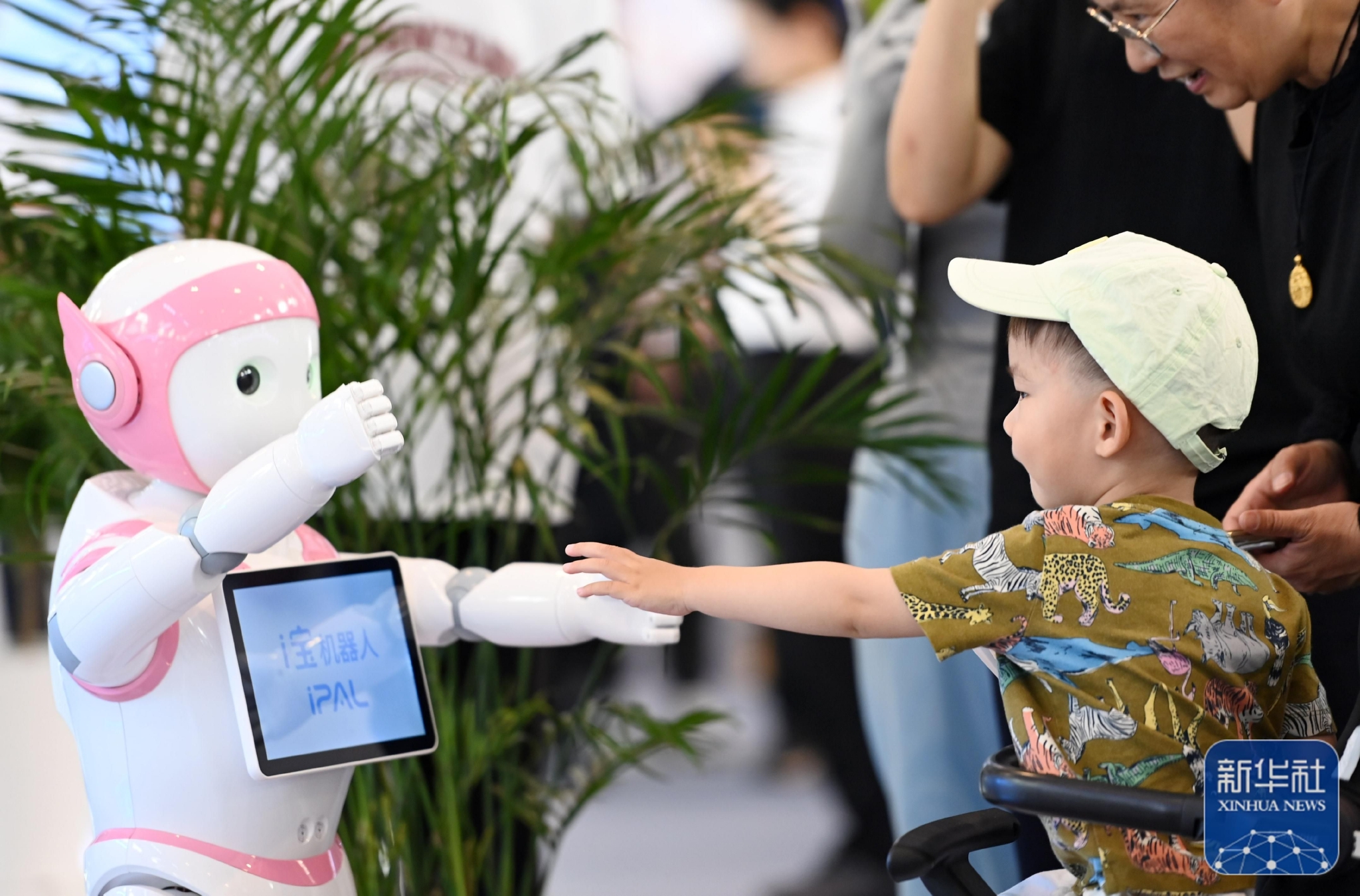 5月19日,一名儿童在第七届世界智能大会智能科技展上和一款机器人互动