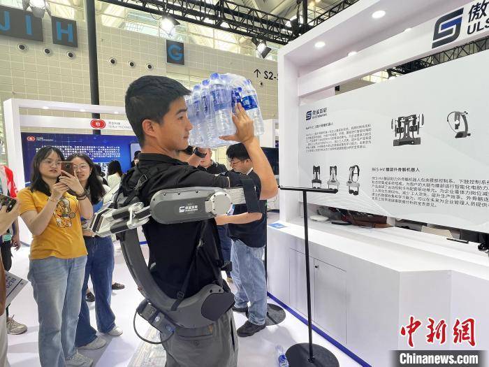 图为展区工作人员展示穿戴"外骨骼"搬起重物. 王君妍 摄