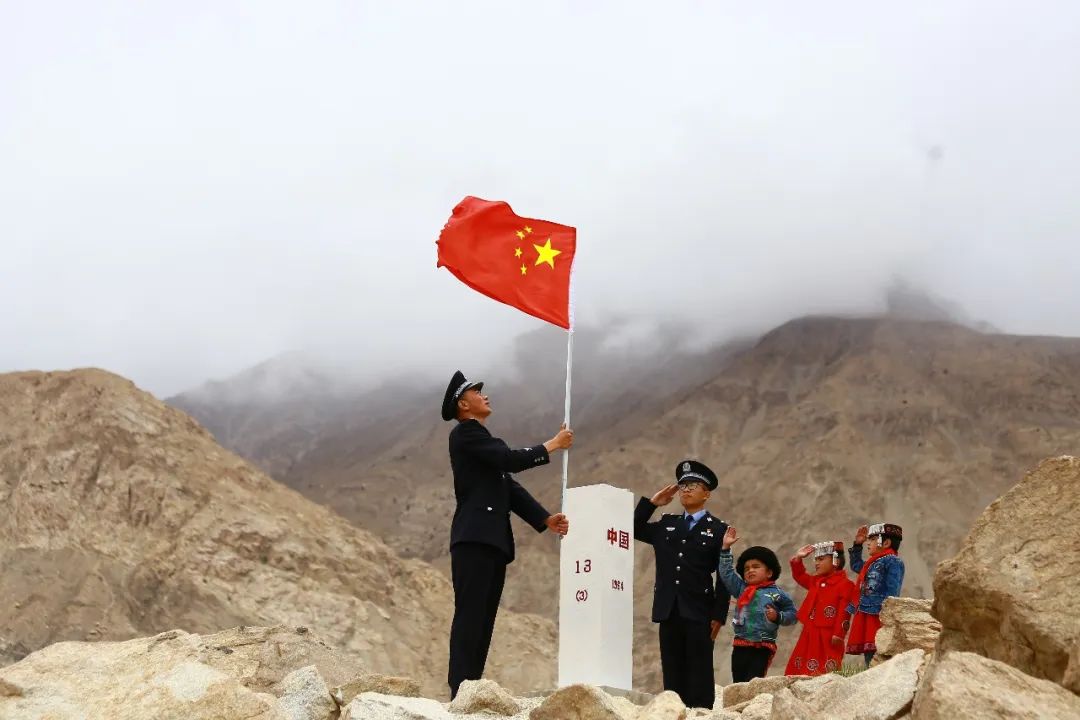 新疆喀什边境管理支队移民管理警察与孩子们向国旗敬礼.(李展朋 摄)