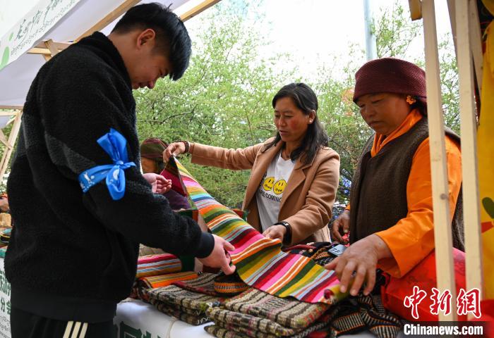 图为活动市集中，游客了解藏族手工氆氇。赵朗摄
