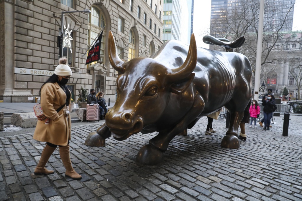 2020年12月21日，在美国纽约，一名戴口罩的女子走过华尔街铜牛。新华社记者王迎摄