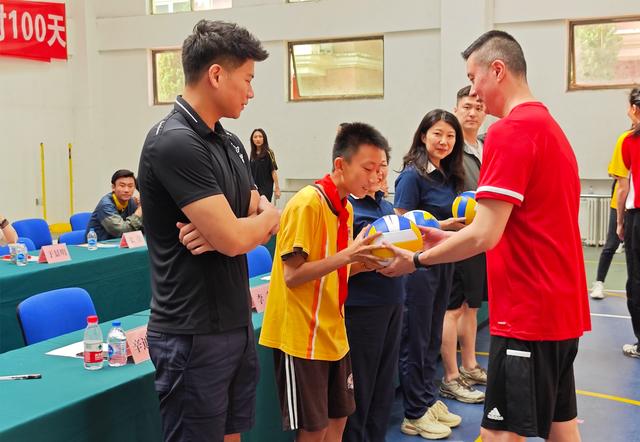 活动现场,世界军人运动会男排冠军成员李春向学校师生代表赠送"礼物".