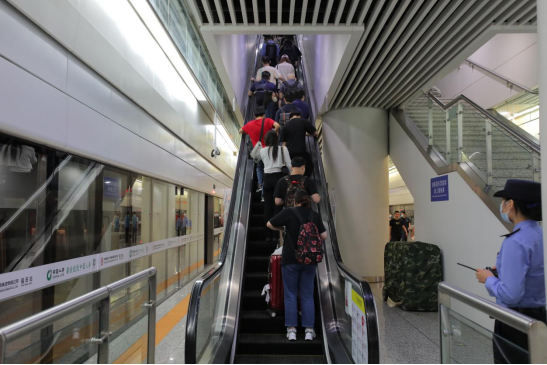 5月25日下午,在福田高铁站,到站乘客拖着行李搭乘同一部扶手电梯前往