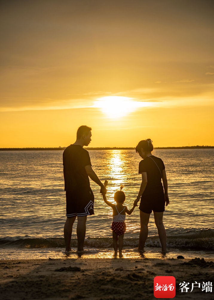 在海口市西海岸的栖海岸露营基地的海滩上,一家三口在戏水.