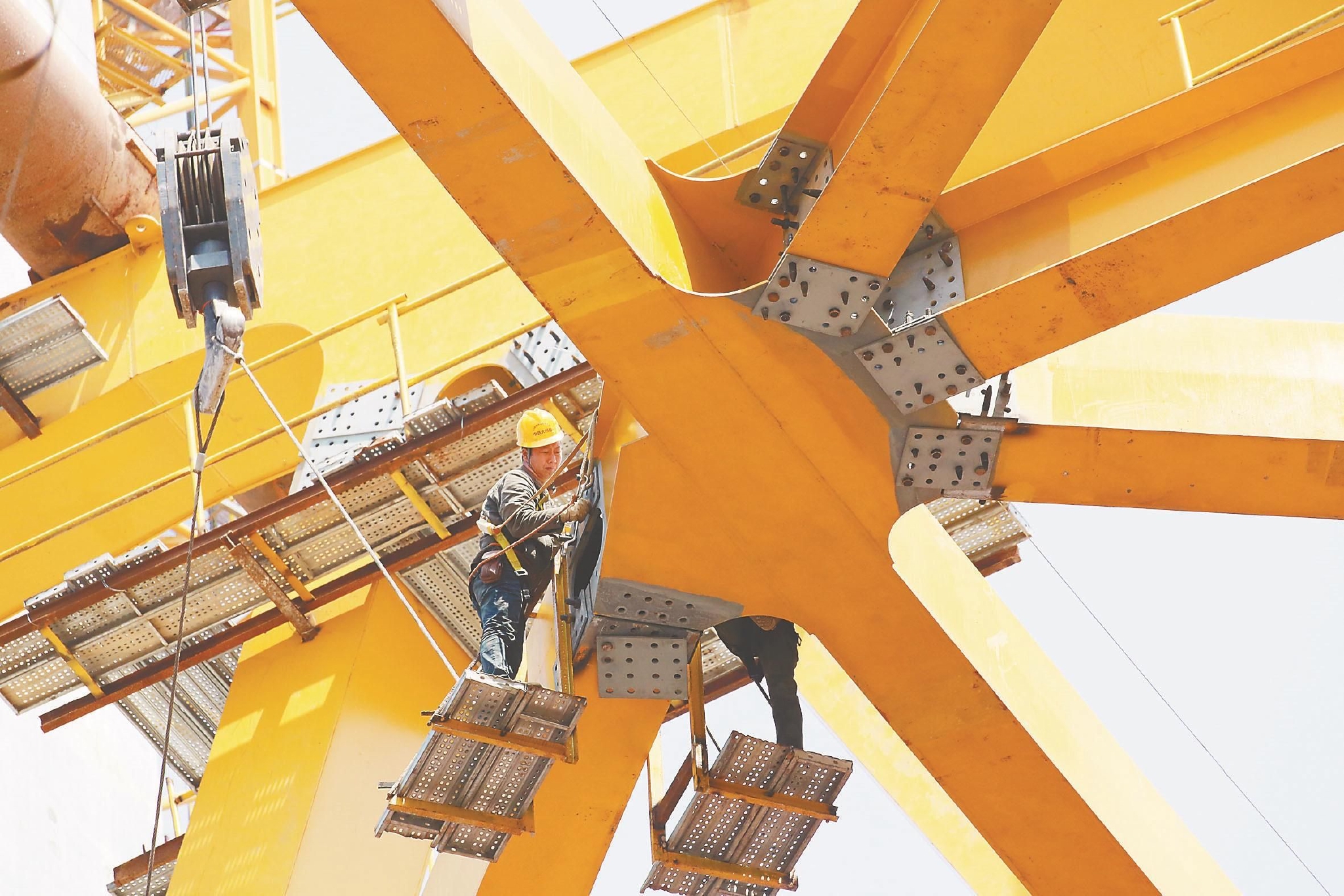 公铁大桥南岸4号墩主塔导梁上,技术工人正在对架梁吊机进行螺栓安装