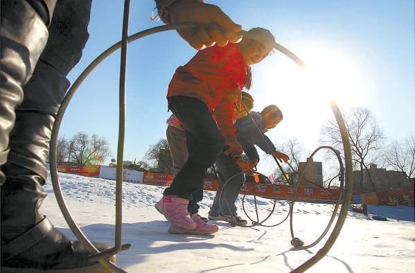 2013年,在玉渊潭公园冰雪游乐区,孩子们参加雪上滚铁环比赛.饶强摄