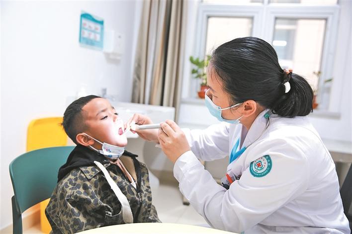 一师医院儿科医生张敏(右)为儿童检查牙齿(摄于4月10日). 黄叶叶 摄