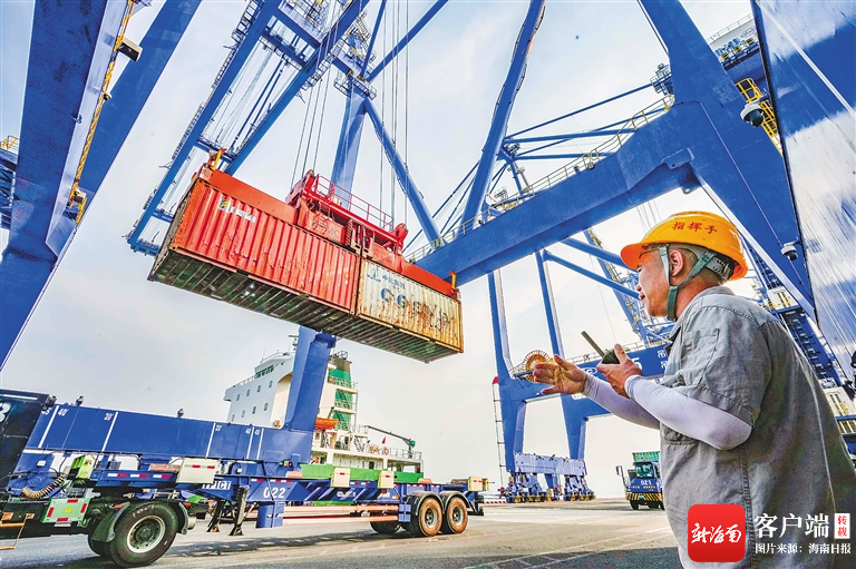 在洋浦经济开发区国际集装箱码头,工人指挥集装箱有序装船.