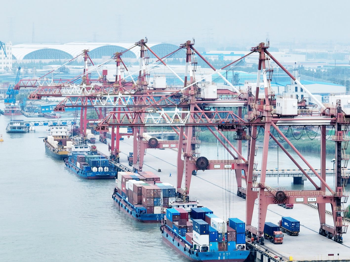 6月4日,货轮在扬州港集装箱码头的泊位上有序装卸集装箱,卡车在堆场