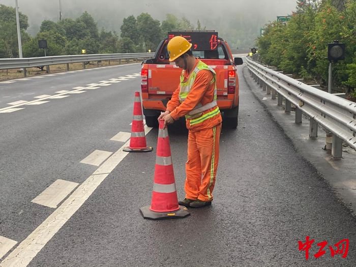 养护站养护员在福银高速上村隧道a道出口的高速路面作业前摆放反光锥