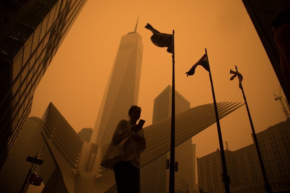 6月7日,一名行人从烟尘笼罩的美国纽约曼哈顿世贸中心附近走过(图片来源:新华社)
