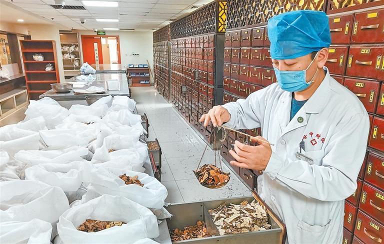 甘肃中医药大学附属医院中药房内药师为患者抓取中药.