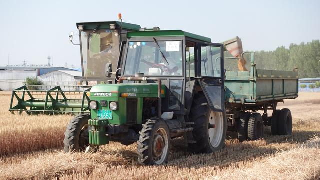 麦粒从收割机管道倾泻而下装进运粮车.房山区窦店镇供图