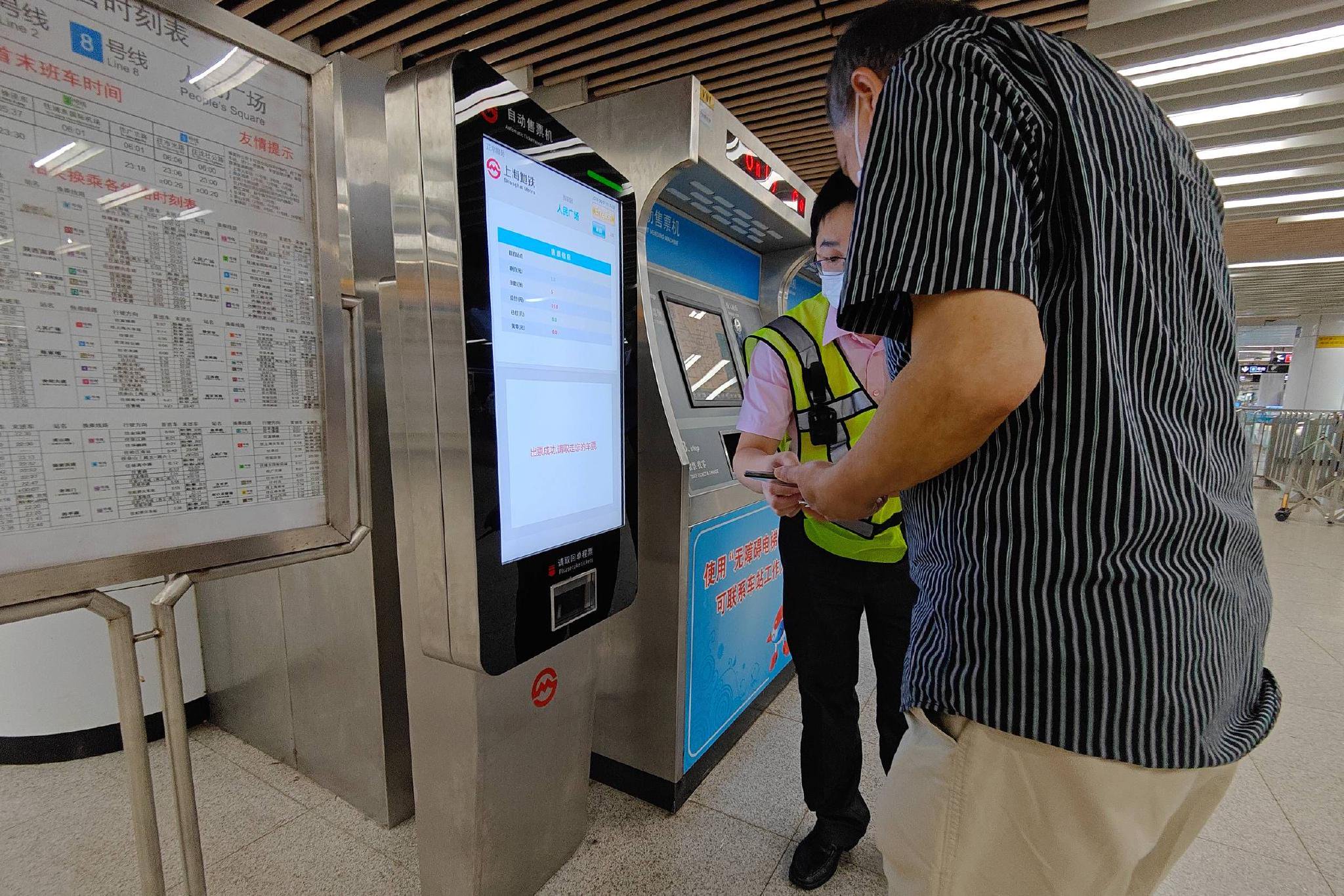 2023年6月1日,上海,黄浦区人民广场地铁站自动售票区,志愿者正协助一