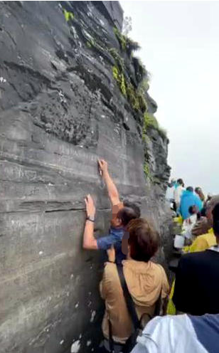 ↑6月18日，游客在梵净山金顶摩崖刻字（网传视频截图）