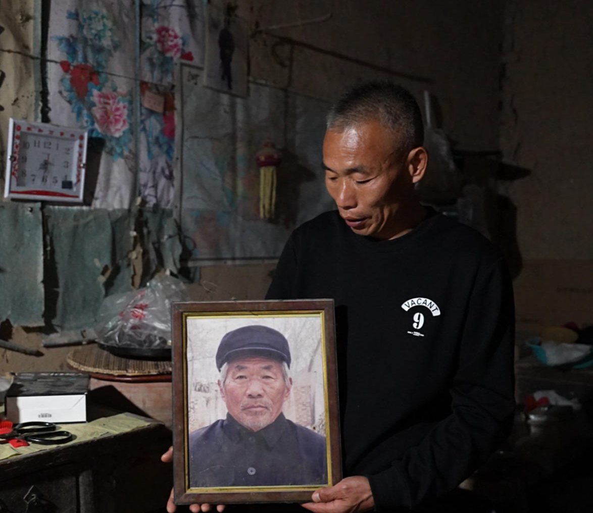 谢哲海端着父亲的遗像