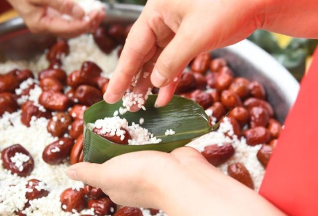 6月18日,在河北省石家庄新乐市建安小区,志愿者和居民一起包粽子.