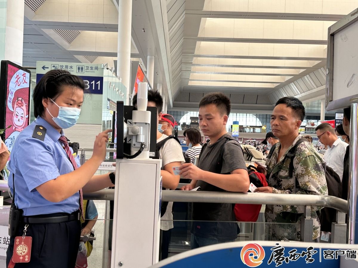 南宁东站工作人员正在为进站旅客审核证件.记者 岑琴 摄