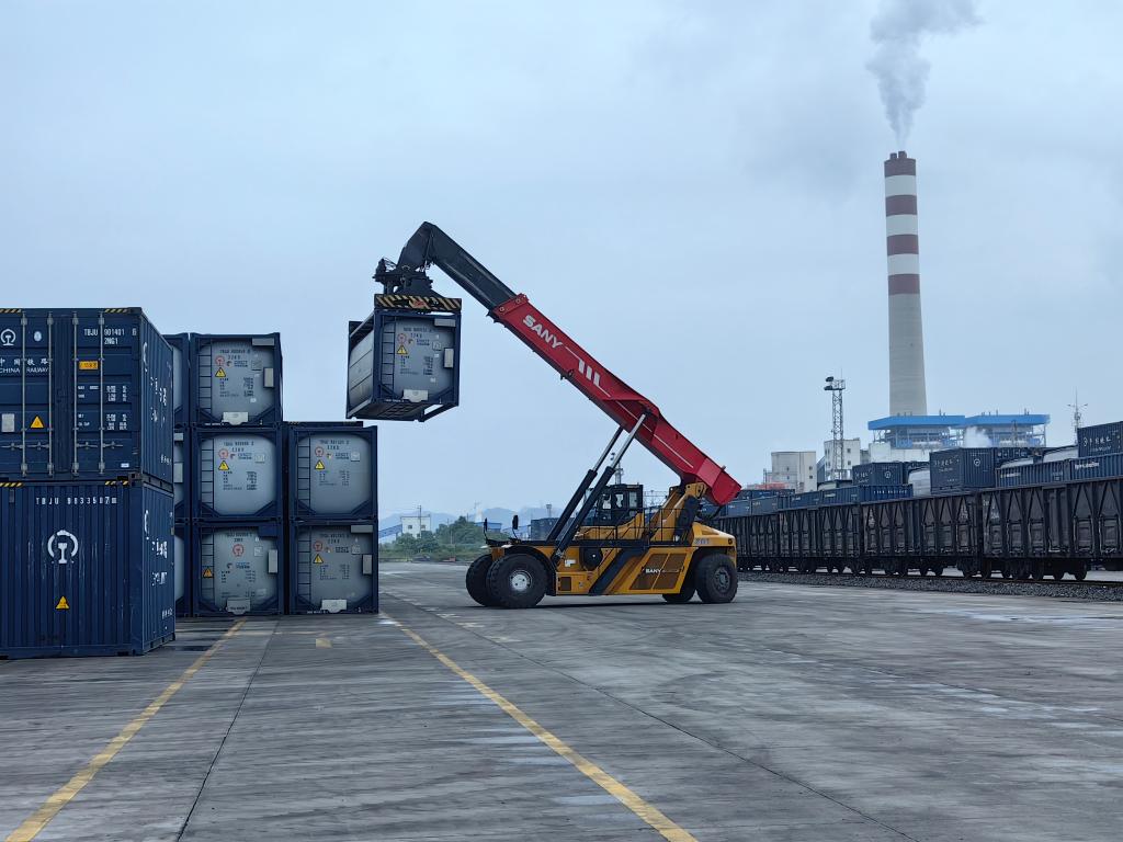 在西部陆海新通道长寿班列的铁路站场,正面起重机将集装箱吊装在列车