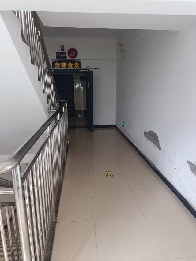 该医院食堂位于医院综合楼二楼,楼梯间入口处写着"营养食堂",门口的