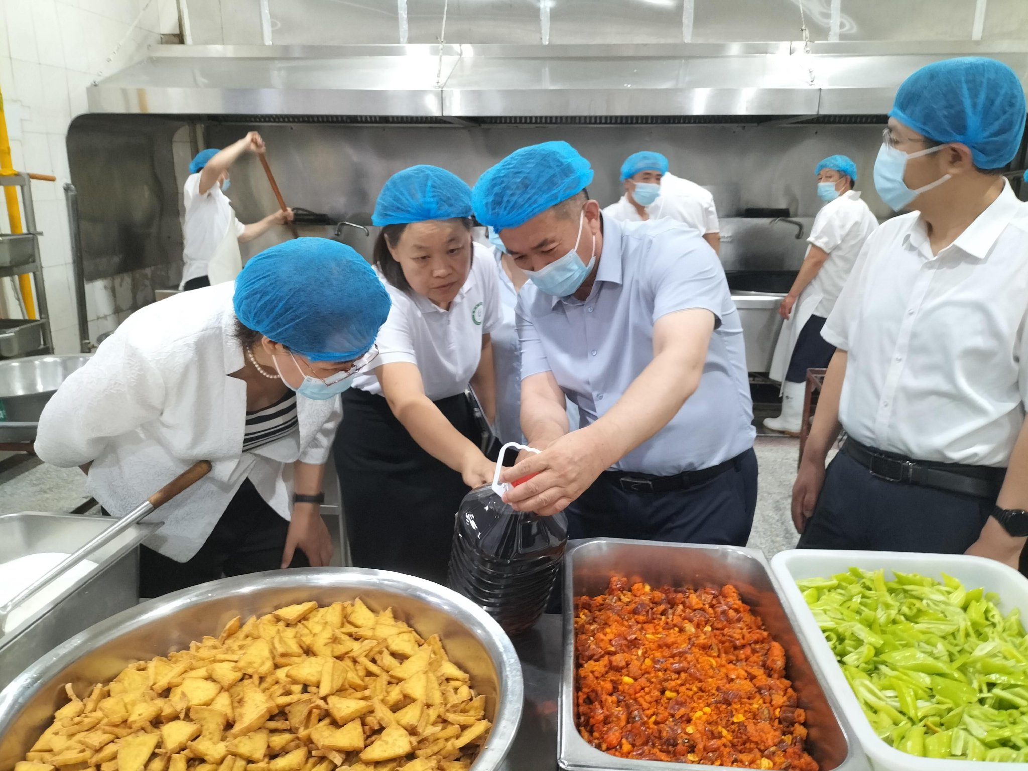 安全示范城市领导小组办公室工作人员在学校食堂后厨检查食用油质量