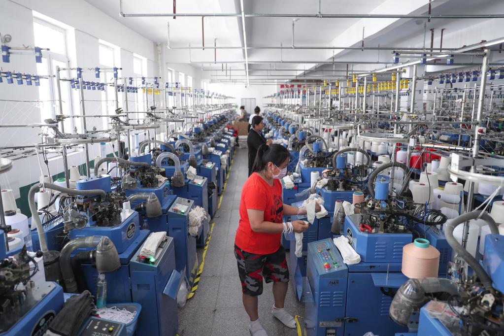 7月5日,工人在位于辽阳市辽阳县小北河镇的金丝雨针织厂加工袜子.