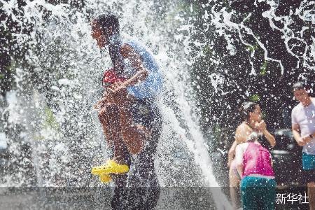 美国得克萨斯州休斯敦，一对父女在高温天气下戏水纳凉。