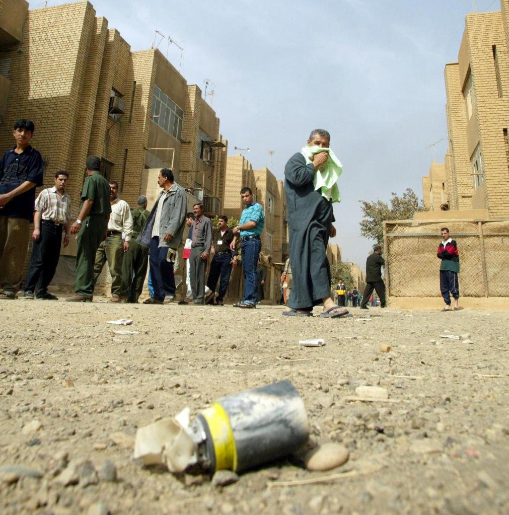 ↑2003年4月5日在伊拉克巴格达南部一个居民区拍摄的照片，人们纷纷绕开一枚集束炸弹的“子炸弹” 新华社发