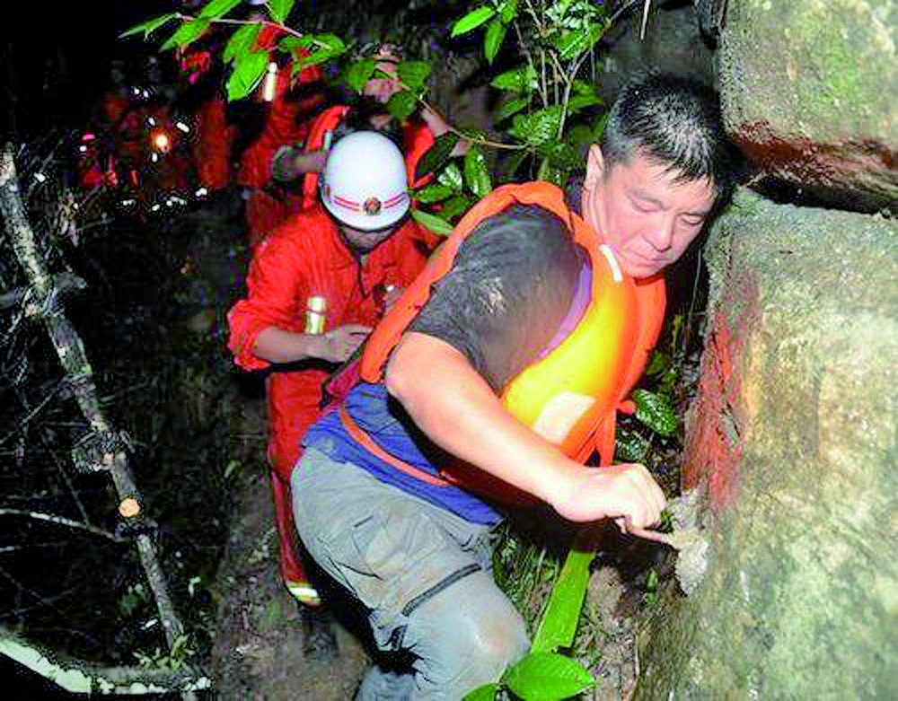 获救驴友（右一）在救援人员帮助下走出峡谷。