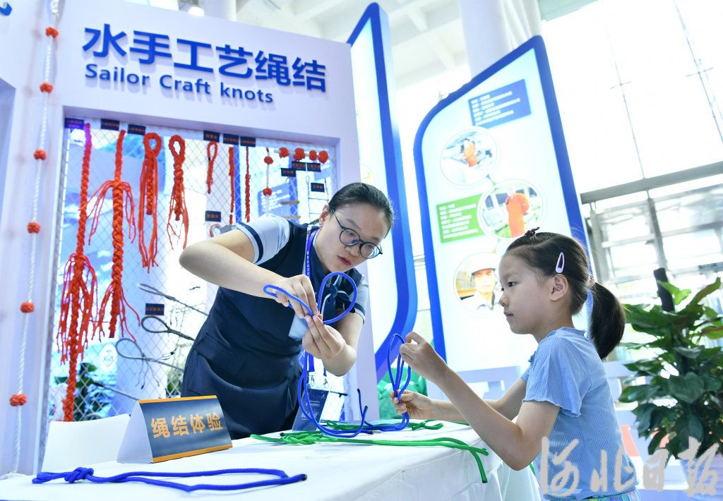 7月11日,小朋友在航海科技博览会上学习打水手绳结.