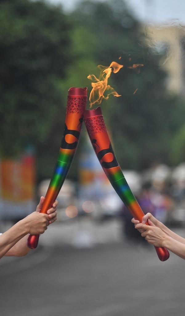 7月14日,两名火炬手在火炬传递中交接.新华社记者 刘坤 摄