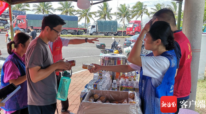 志愿者给货车司机发放矿泉水和饼干等物品。记者 王康景 摄