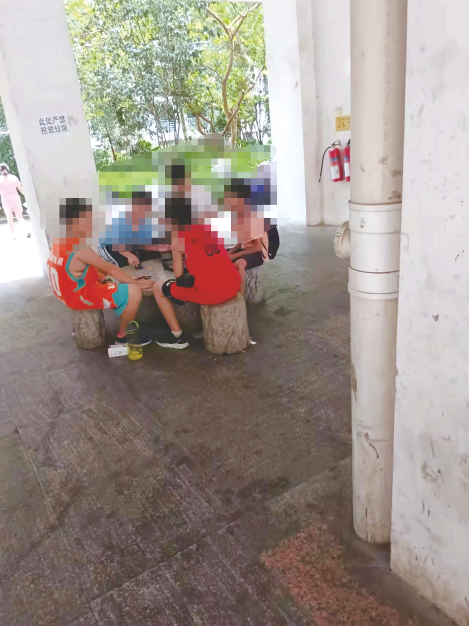     孩子们聚在小区石桌上玩“拍烟牌”游戏    本报记者 郑芳 摄
