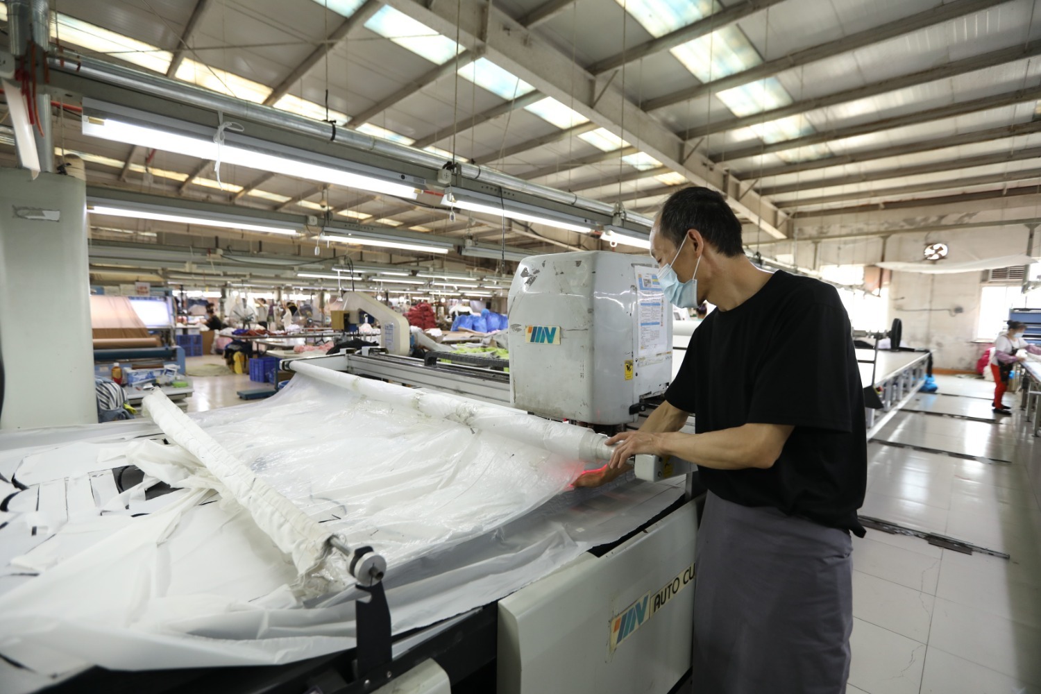 摄)图为在河北省香河县瑞康衣业有限公司车间,工人使用自动裁床对布料