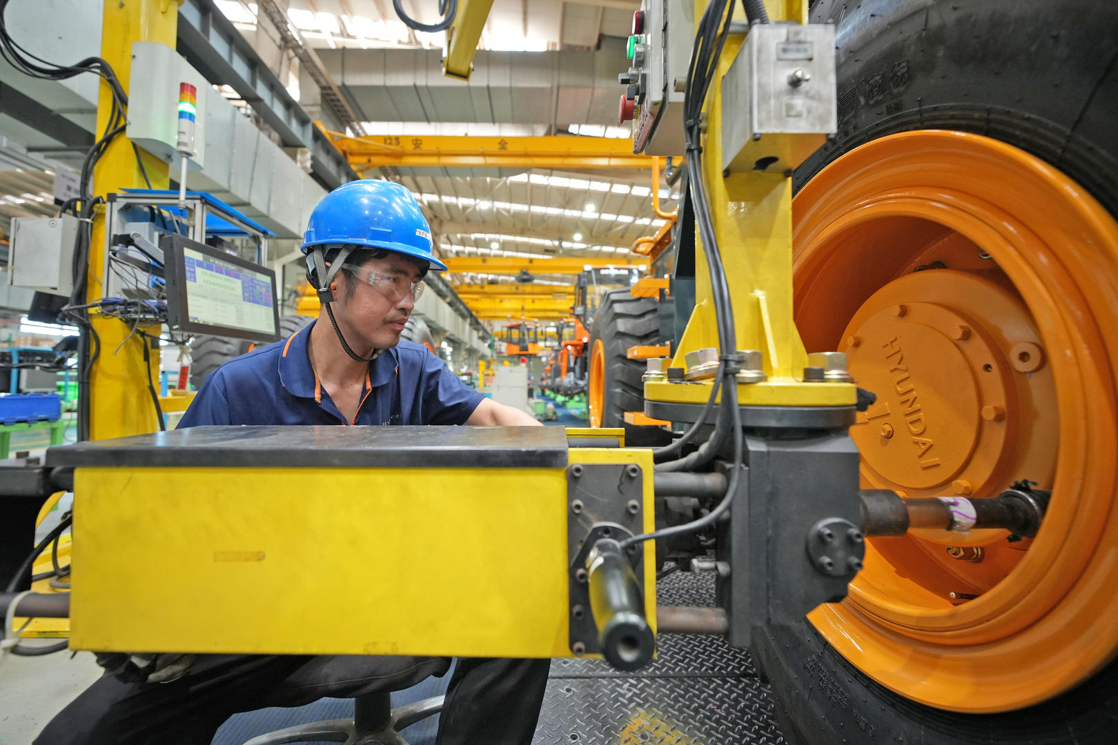 ↑2023年7月，工人在生产线上装配装载机。图据视觉中国