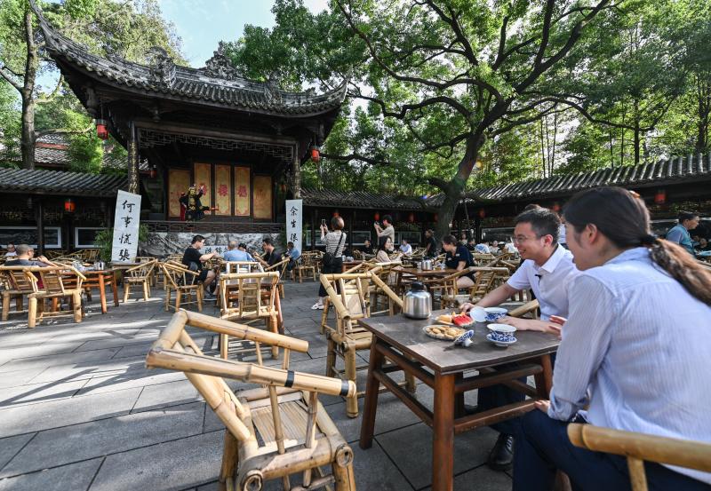 7月14日,在成都高新区铁像寺水街,游客在茶铺体验当地特色盖碗茶.