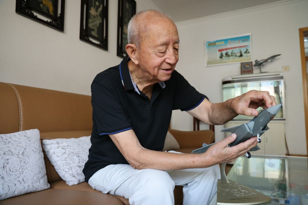 ↑2023年7月24日，新中国第一代飞行员陶伟在家中擦拭歼－20飞机模型。新华社发（张瑞　摄）