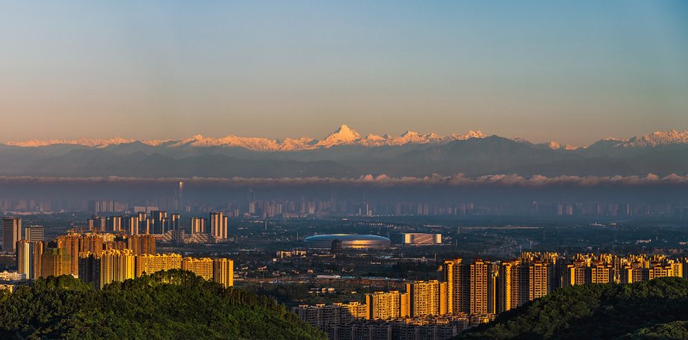 这是2021年6月4日清晨拍摄的成都市建筑群与远处的雪山.