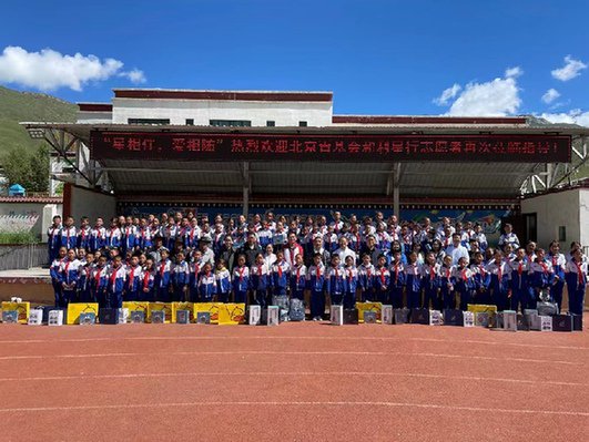 玉树新寨小学操场上，孩子们和利星行汽车公益志愿服务队、北京青少年发展基金会一行合影。