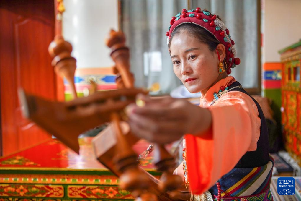 堆谐排练前,格桑卓玛在家中为扎木念调音(8月4日摄).