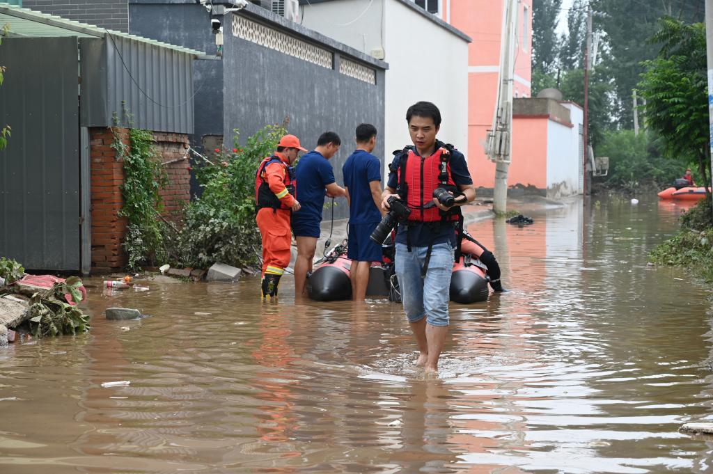 8月3日，记者牟宇在码头镇沙窝村内涉水拍摄。
