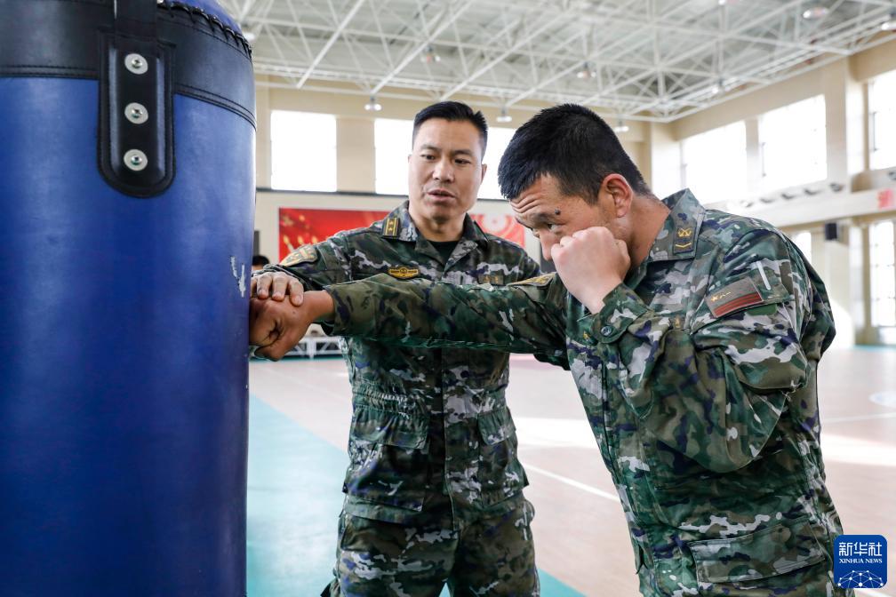 武警新疆总队某支队副参谋长成林(左)在搏击馆内为特战队员纠正恩作