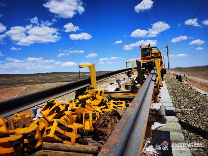 6月7日,淖毛湖至将军庙铁路施工现场,施工人员在加紧铺轨(资料图片).