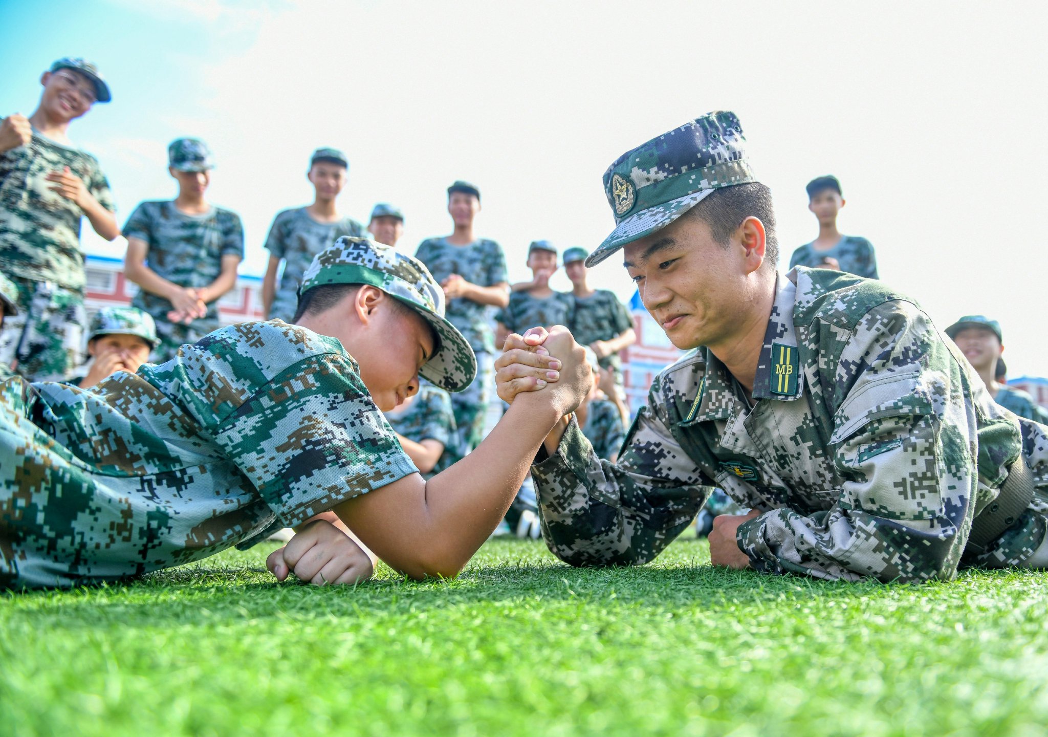 在湖南省永州玉潭高级中学,高一新生在军训休息间隙与教官进行"掰手腕